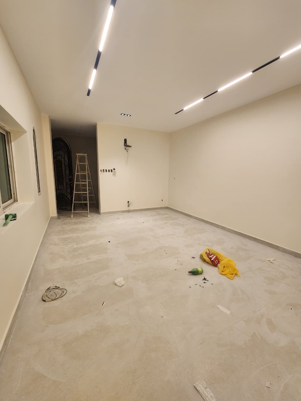 Long view of the living room showing the carved entry door and the wall pre-wired for the television.
